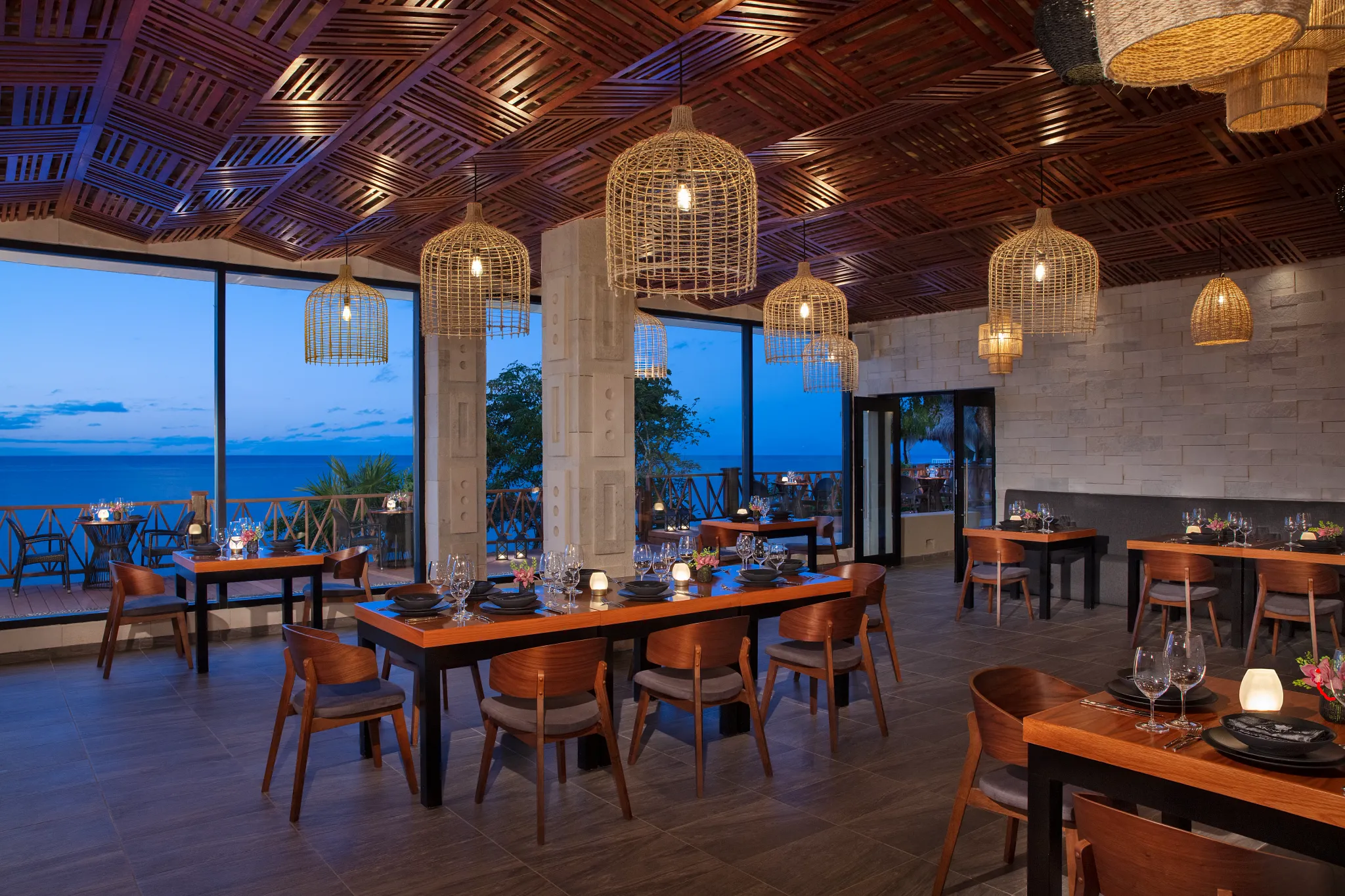 Annatto restaurant at Dreams Cozumel Cape Resort & Spa featuring ocean-view dining, woven pendant lighting, and elegant Asian-Mayan fusion ambiance.