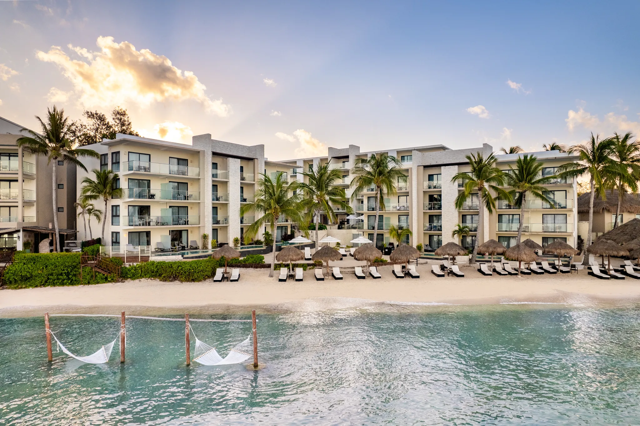 Beachfront hammocks over turquoise water at Dreams Cozumel Cape Resort & Spa in Cozumel, Mexico.