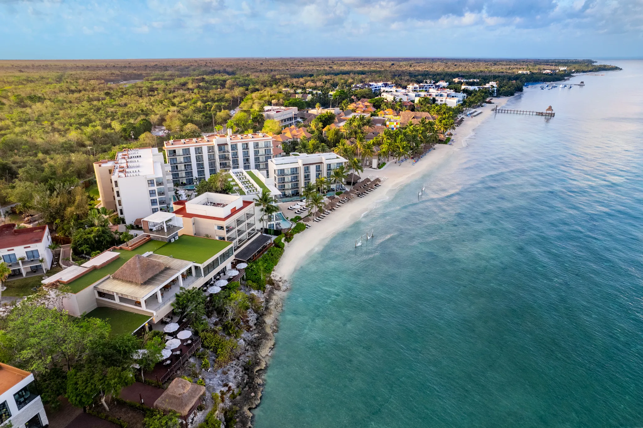 Elevated drone view of Dreams Cozumel Cape Resort & Spa surrounded by lush greenery and the Caribbean Sea.