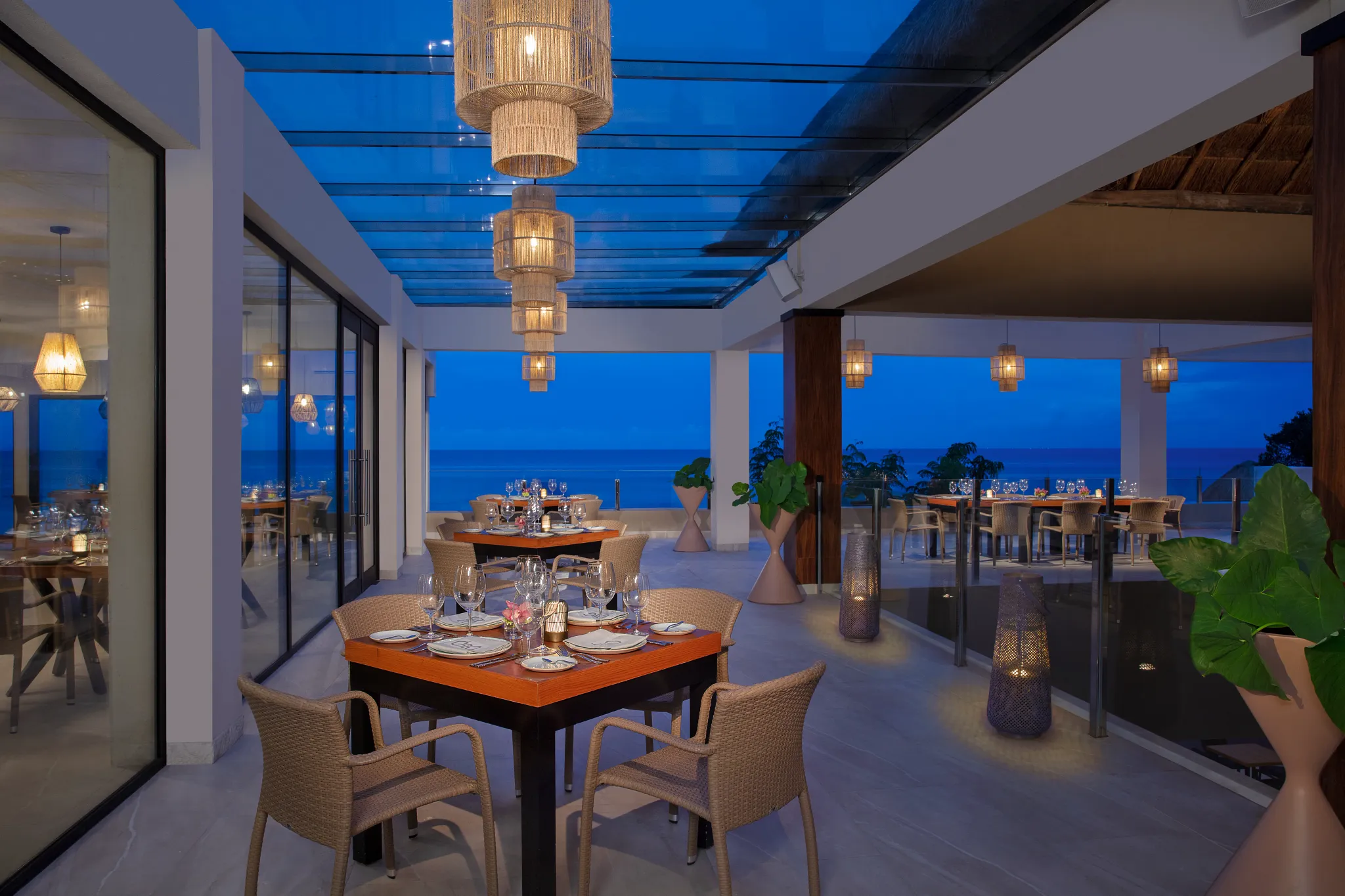 Outdoor dining terrace at Olio restaurant at Dreams Cozumel Cape Resort & Spa overlooking the ocean at sunset.
