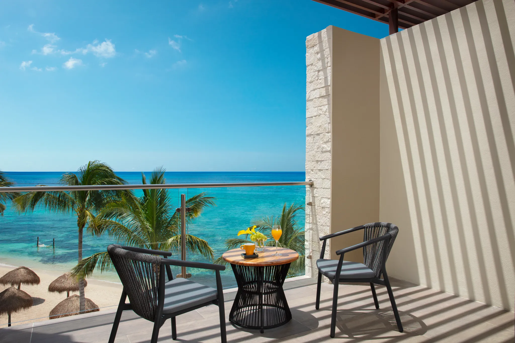 Oceanfront balcony with seating overlooking turquoise Caribbean waters at Dreams Cozumel Cape Preferred Club Junior Suite.