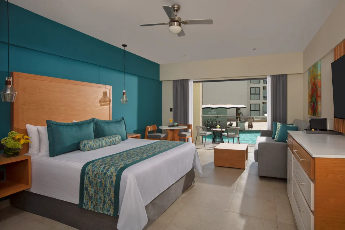 Preferred Club Junior Suite Pool View with king bed and furnished balcony at Dreams Cozumel Cape Resort & Spa overlooking the pool.